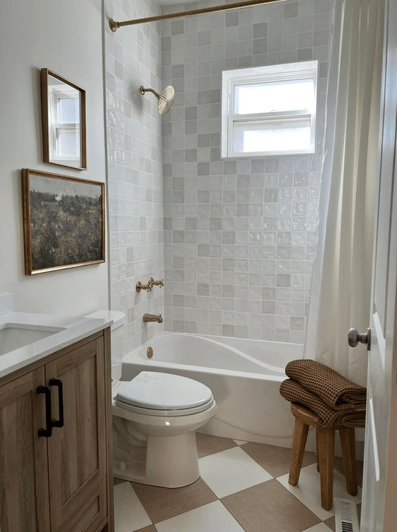 a neutral guest bathroom clad with Zellige tiles, with beige and white checked floors, stained furniture and a gallery wall