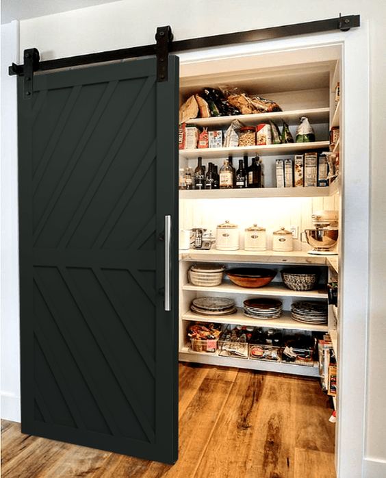 a pantry with a black barn door is a cool solution for a farmhouse space, it will accent it and add contrast and color