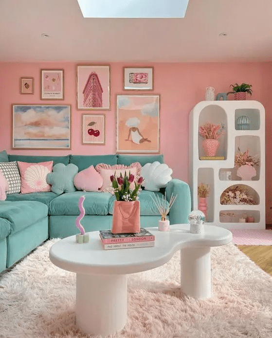 a pastel dopamine decor living room with pink walls, a green sectional, pastel pillows, a pretty gallery wall and a storag eunit