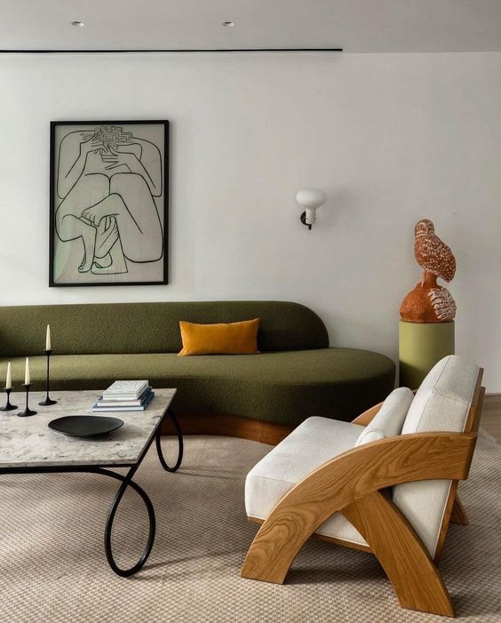 a refined contemporary living room with a green curved sofa, a creamy chair, a coffee table and some refined decor