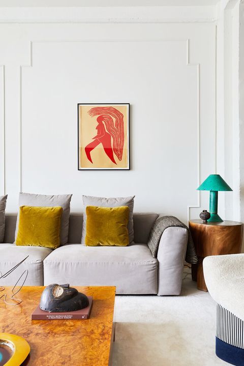 a refined living room with molding, a grey sofa with mustard pillows, a coffee table, a chair, a side table and a bold artwork