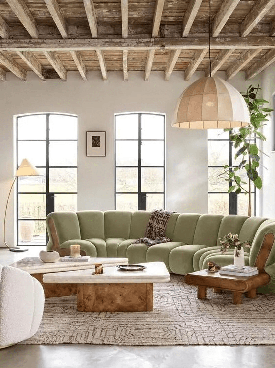 a refined living room with tall windows, a light green cotton sectional, a duo of coffee tables, a couple of chairs
