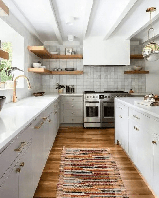 A refined neutral mid century modern kitchen with a grey zellige tile backsplash, white stone countertops, a hood and open shelves