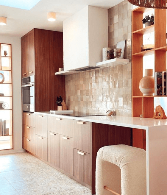 A rich stained kitchen with a tan Zellige tile backsplash, white countertops, a white hood and a lovely bent stool