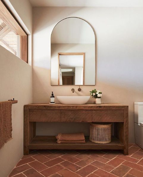 a rustic bathroom with neutral walls, a terracotta tile floor, a stained vanity, a clerestory window for natural light