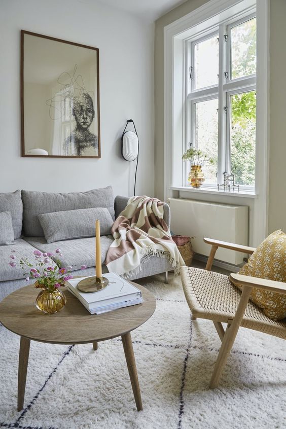 a serene eclectic living room with a grey sofa, a woven chair, a coffee table and some art and lamps is amazing