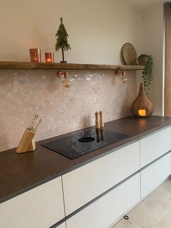 a sleek minimalist kitchen with white cabinets, black countertops, a pink scallop Zellige tile backsplash and an open shelf