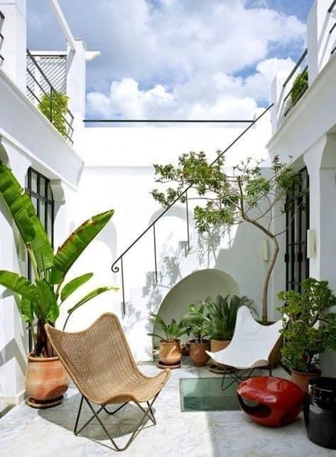 a small and cool patio with butterfly chairs, a portable fireplace, potted plants and trees is super cool