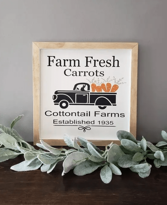 a small spring sign with a truck carrying carrots, with some letters and in a simple wooden frame