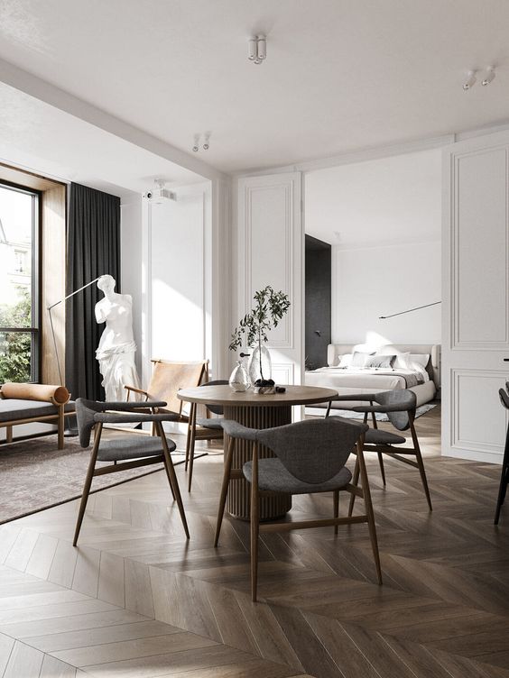 a sophisticated Parisian space with white molding, a dark chevron floor, a lovely dining space, a daybed, some decor and dark curtains
