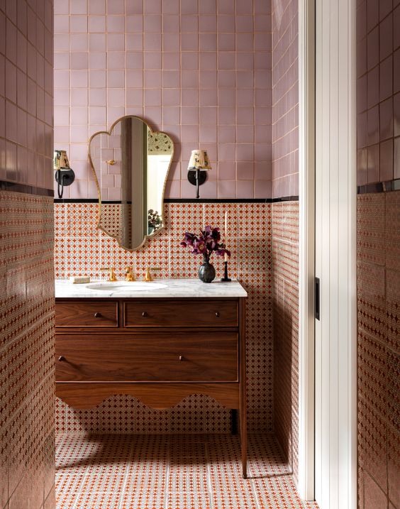 a sophisticated bathroom clad with pink Zellige and red printed tiles, a stained vanity with a scallope edge and a beautiful mirror