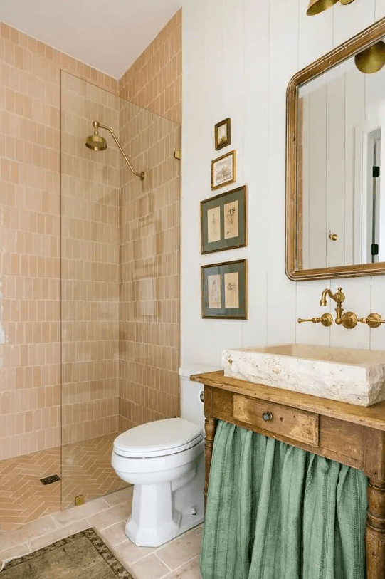 a whimsical bathroom with terracotta tile in the shower, a shabby chic vanity with a curtain, a mirror and a stone tub