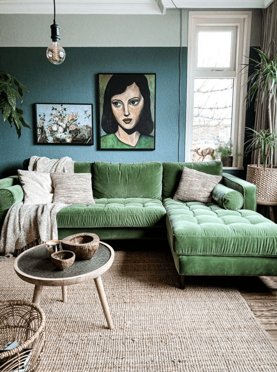a whimsical living room with a blue accent wall, a green sectional, a jute rug, a coffee table, some art and potted plants