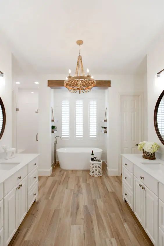 a white farmhouse bathroom with a wooden and wooden bead chandelier, a tub, open shelves, a side table and some cool decor