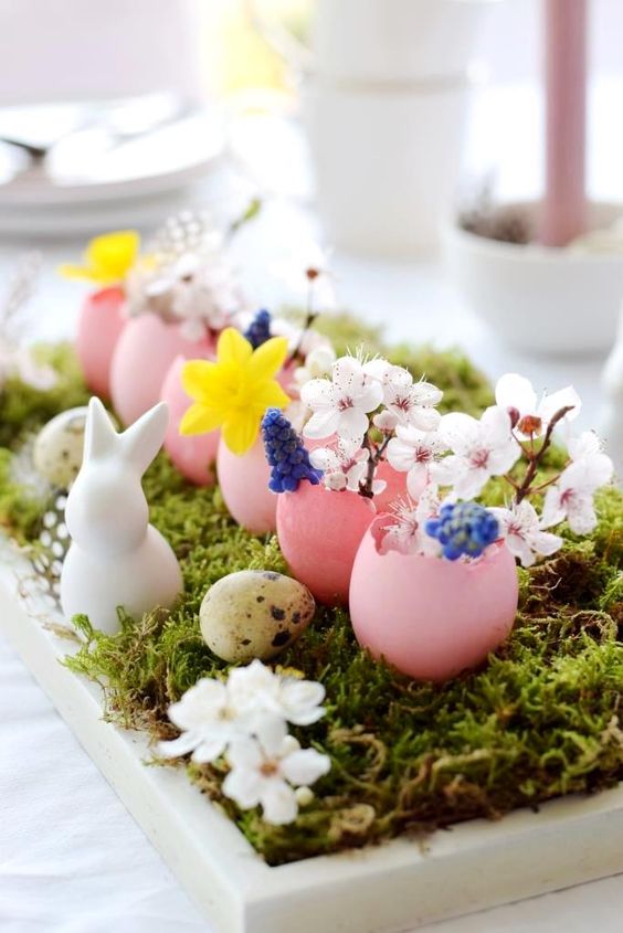 an Easter centerpiece of a tray with moss, speckled eggs, bunnies, pink egg shells with blooms and feathers is amazing