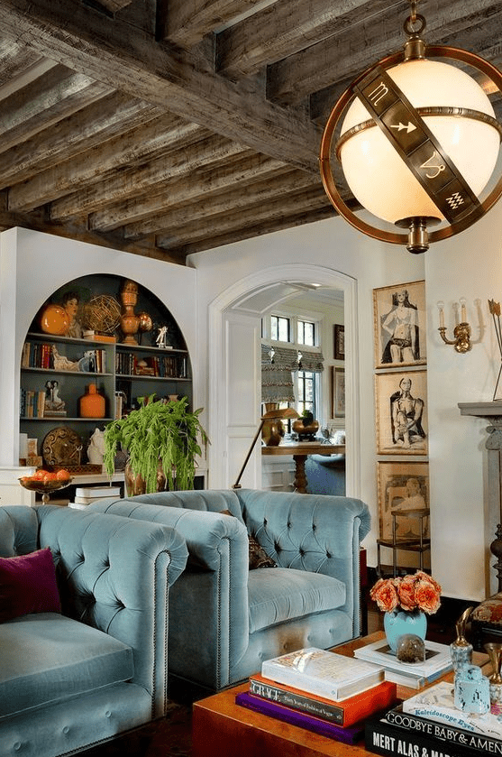 an eclectic living room with light blue chairs, an arched bookcase with books and decor, a unique lamp and some art