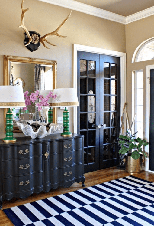 black French doors, a black sideboard and a navy and white striped rug create a cohesive look in the space