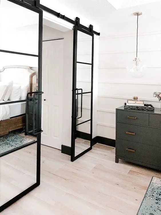 black barn doors with mirror panes are a cool idea for a modern farmhouse or rustic space, and mirror enlarges the room visually
