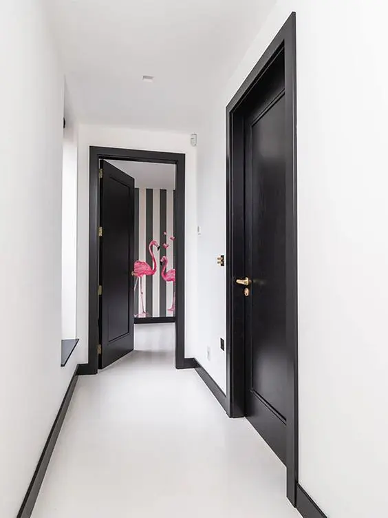 black doors accent this white corridor and gold handles add chic to it, this way the space looks much more elegant and chic