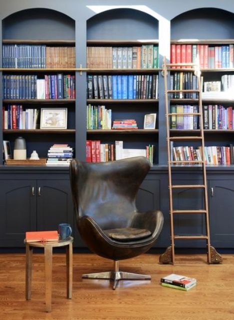 graphite grey arched bookcases, a copper ladder and a cool black leather Egg chair compose a gorgeous reading nook