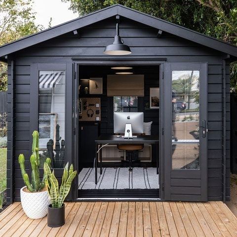 a black modern farmhouse shed with a home office, a desk, a leather chair and some gallery walls is amazing