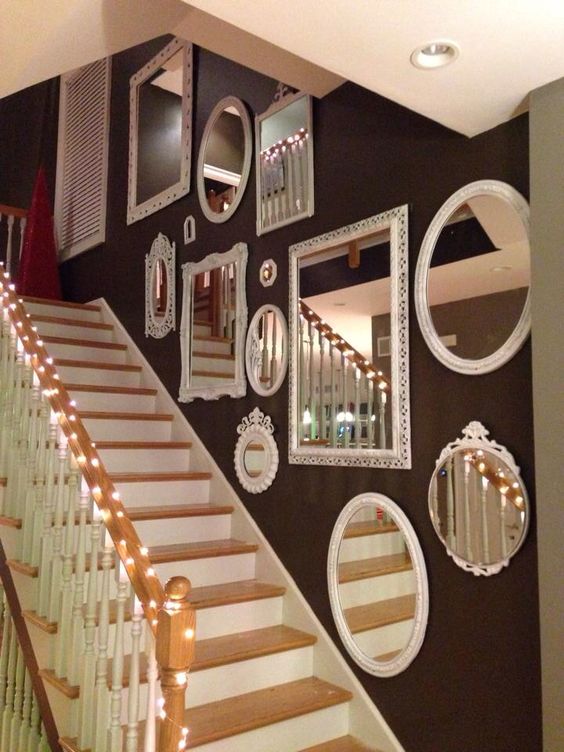 a black wall over the staircase with a mirror gallery wall with chic white frames is amazing