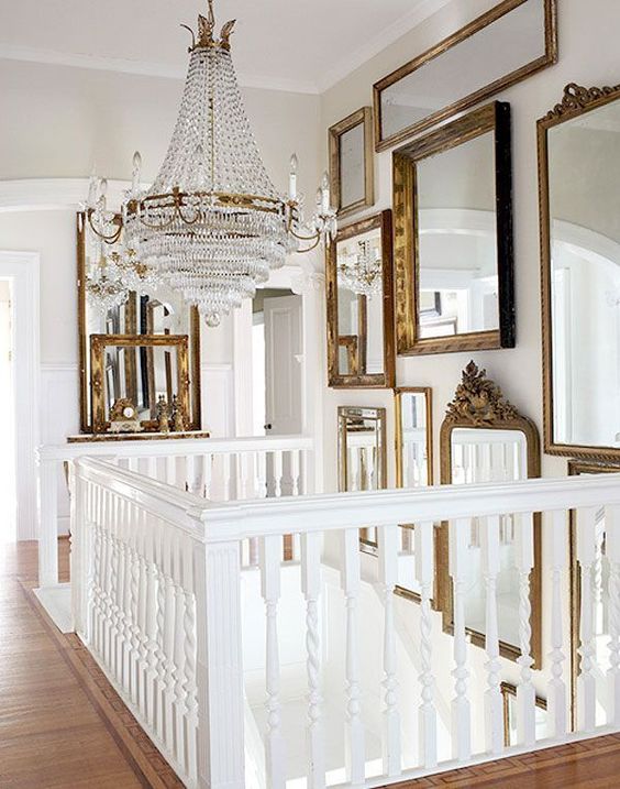 a blank wall over the stairs with gorgeous mirrors in vintage gold frames and a large and heavy crystal chandelier