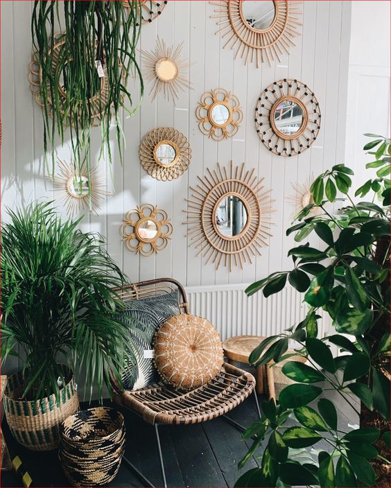 a boho balcony with a rattan chair and a pillow, potted plants and a gallery wall of mirrors in boho frames