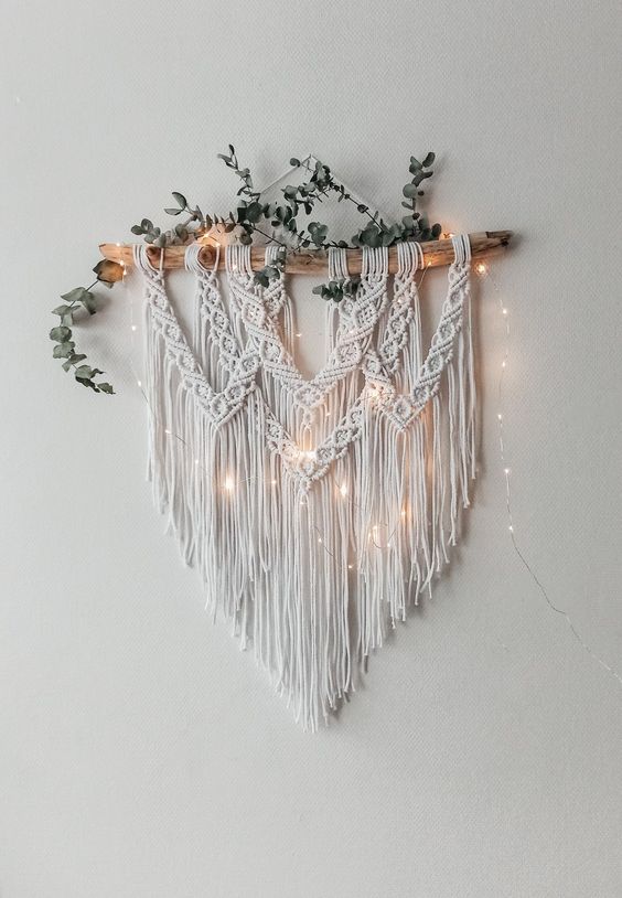 a boho wall decoration of macrame and frigne, lights and faxu greenery is a lovely idea for a boho space