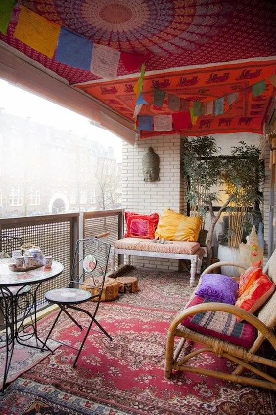 a bold boho balcony with a colorful ceiling, rattan furniture, colorful pillows, wrought furniture, bold banners