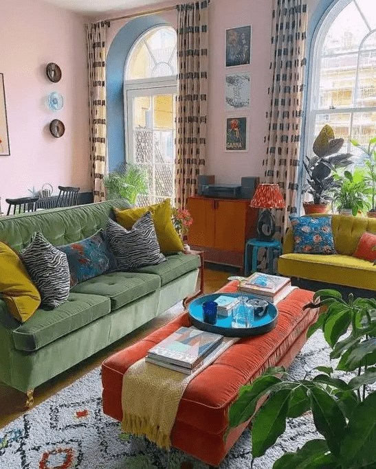 a bold eclectic living room with pink walls, a green sofa, a neon yellow loveseat, an orange ottoman, potted plants and bright artwork