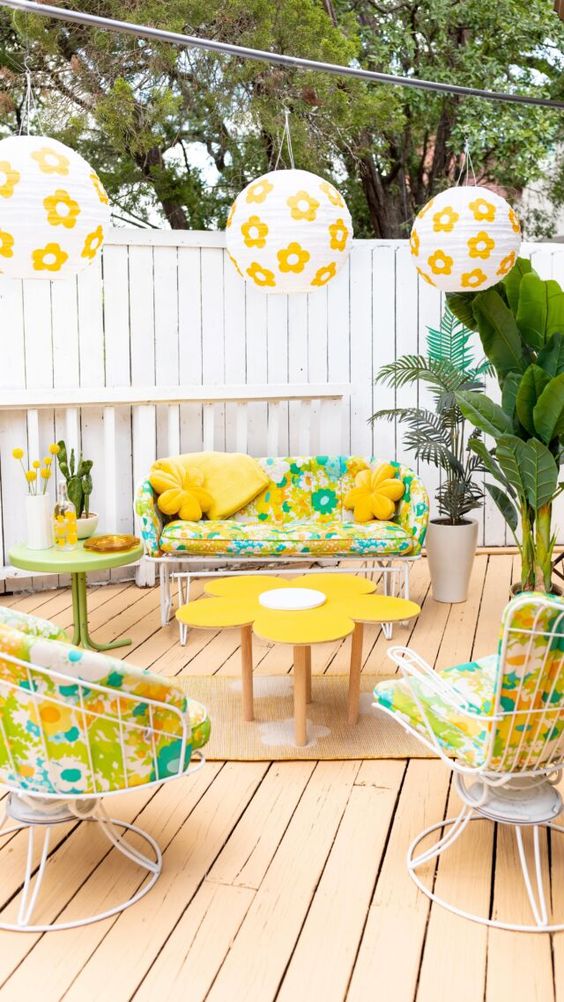 a bold terrace with colorful floral print seating furniture, a coffee table and some floral print lanterns