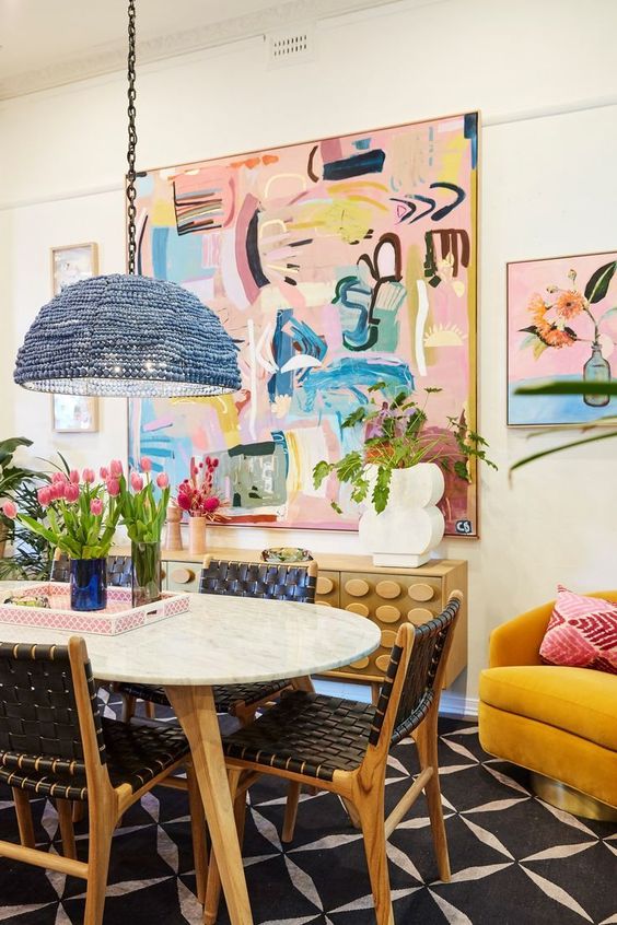 a bright and eclectic dining room with a yellow chair, colorful pillows, a blue bead lamp and some colorful art