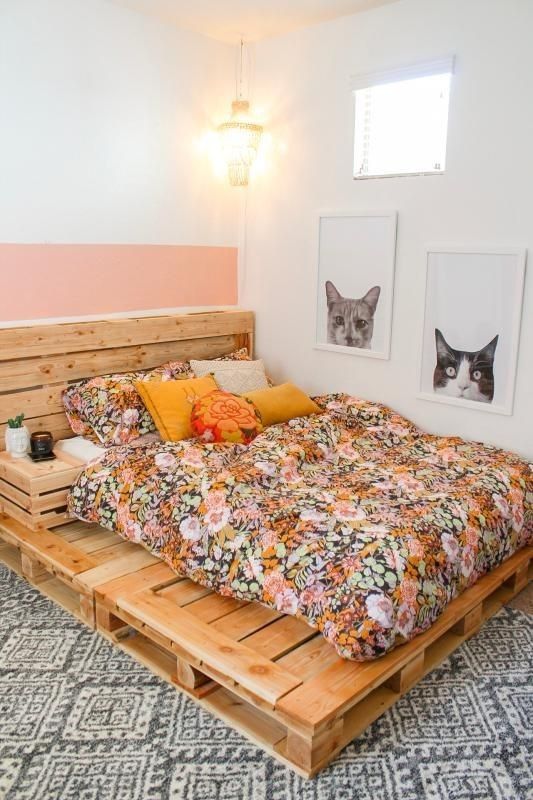 a bright bedroom with a pallet bed and colorful bedding, a lamp and some artwork is a cool and fun space