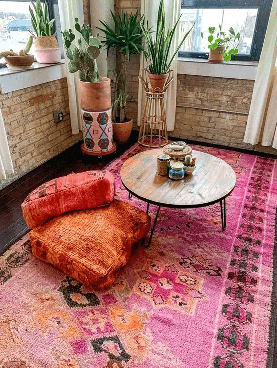 a bright boho nook with a bold rug, colorful cushions, a table and some potted plants and cacti