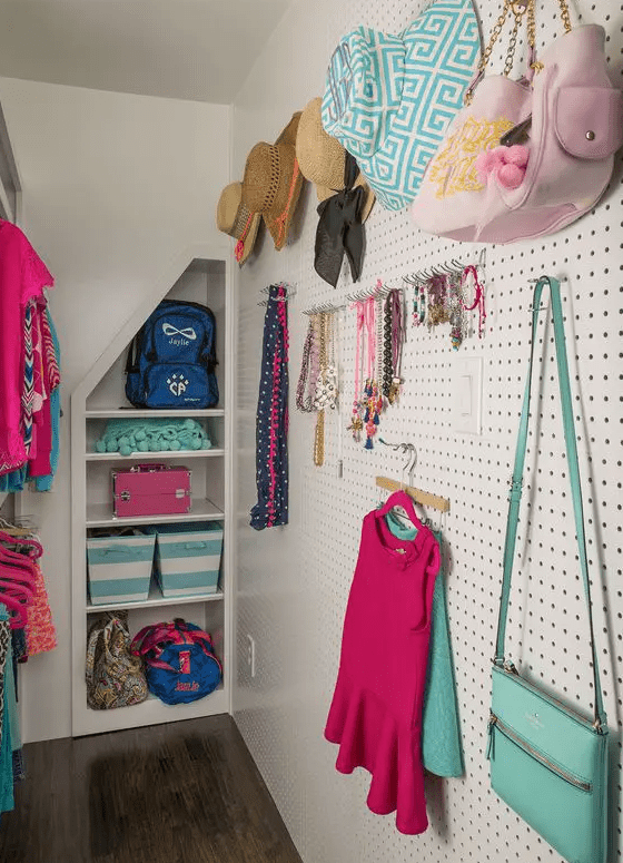 a bright kid's closet with a pegboard and hooks, with built-in shelves and a makeshift closet in the corner