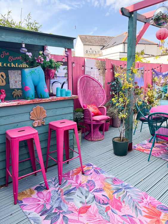 a bright terrace with hot pink furniture, bright rugs, pendant lamps and colorful decor and blooms is playful and fun