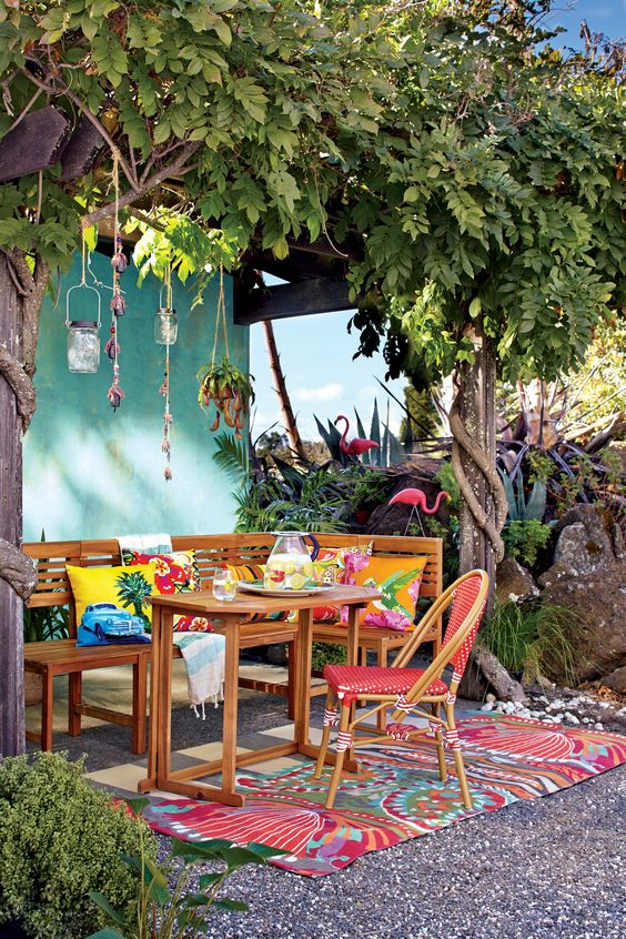 a bright terrace with wooden furniture, colorful pillows and a rug, pendant lanterns on the trees is a cool space