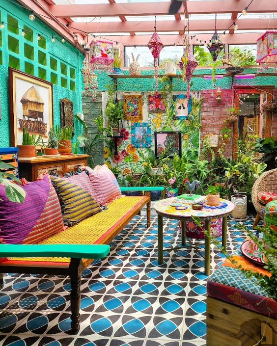 a colorful boho terrace with a tiled floor, a bright sofa with pillows, emerald walls, pendant lamps and potted plants is wow
