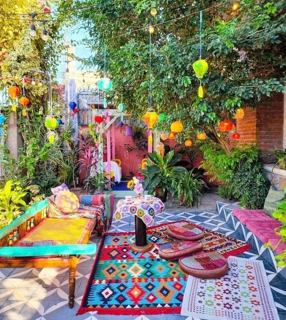 a colorful boho terrace with a woven daybed and colorful pillows and rugs, bright pendant lanterns with tassels