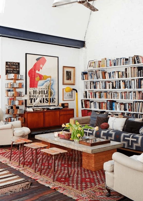 a colorful eclectic living room with open bookshelvesm bright printed textiles, neutral furniture and touches of mid-century modern