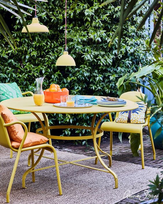 a colorful terrace with yellow furniture, bright pillows, pendant lamps and a jute rug is welcoming and cool