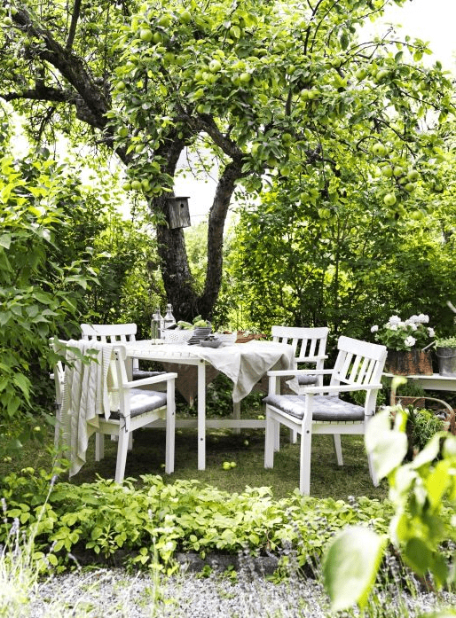 a cozy dining area done with IKEA furniture under the trees, with blooms and greenery around is cool