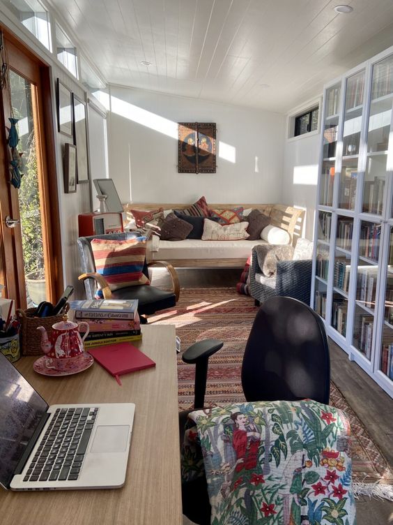 a cozy shed home office with a desk, a chair, a boho rug, a sofa and a rocked chair is very cool and welcoming