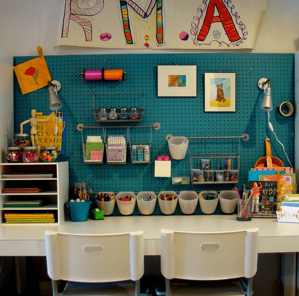 a craft room done with a teal pegboard done with shelves, railings, bold art, some lamps and other stuff is more effective