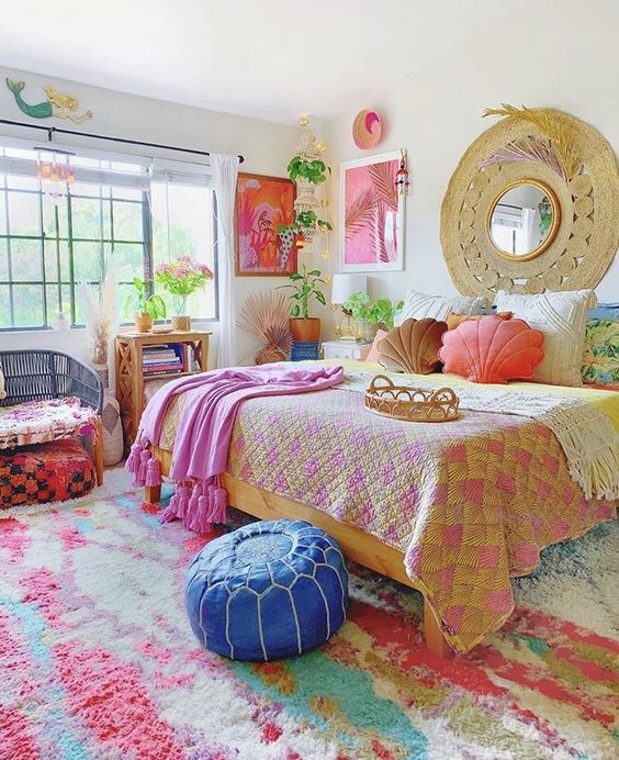 a dopamine decor bedroom with a colorful rug, a blue pouf, a bed with colorful pillows and some bright artwork