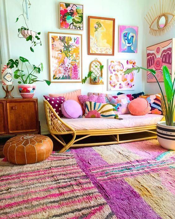 a dopamine decor living room with a rattan sofa with colorful pillows, a bright rug, a colorful gallery wall and some potted plants