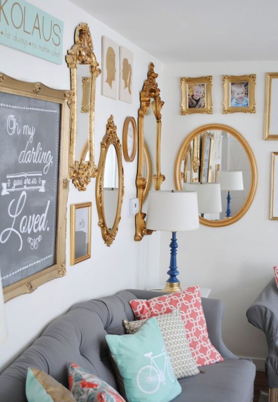 a farmhouse living room with a grey sofa and colorful pillows, a mirror gallery wall with gold frames is amazing