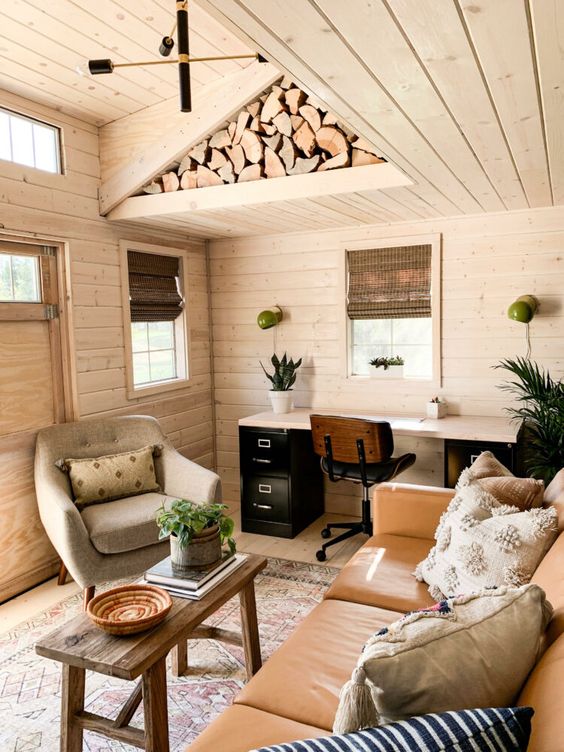 a farmhouse shed with a desk, a leather sofa with pillows, a comfy chair, a coffee table and some stylish decor