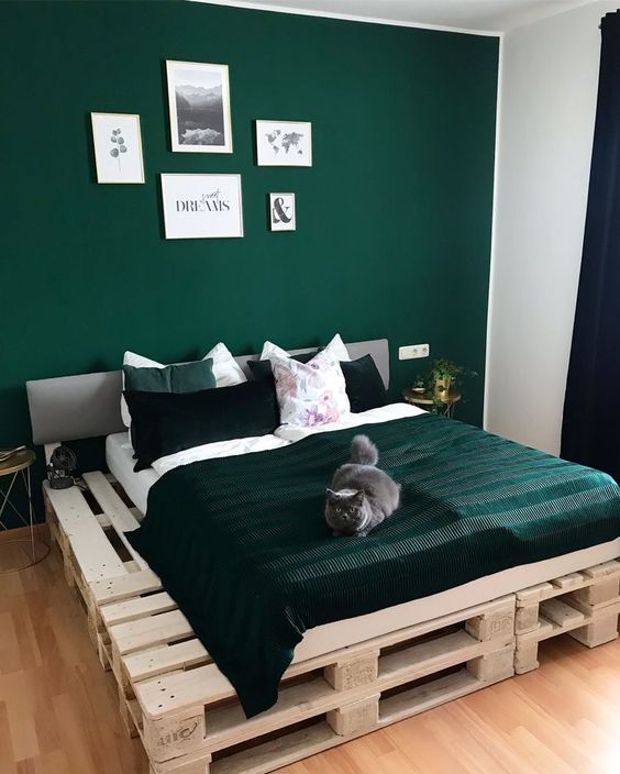 a green bedroom with an accent wall, a pallet bed with green bedding, nightstands and a gallery wall is cozy and cool
